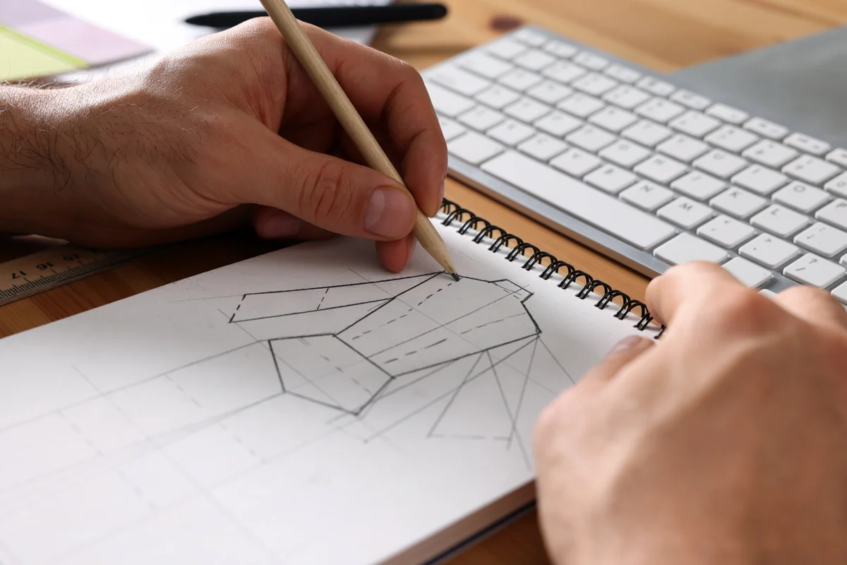 Sketching garment patterns beside a computer