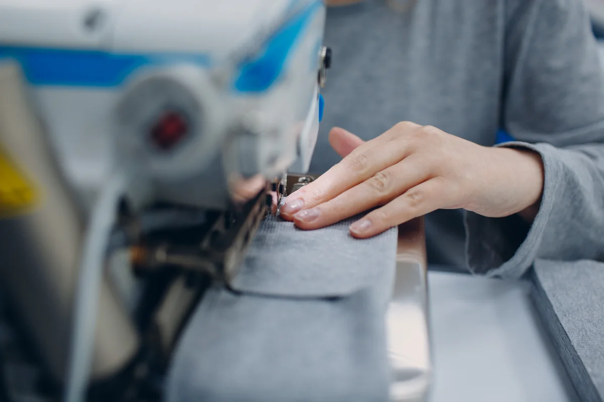 Carefully guiding fabric through an industrial sewing machine