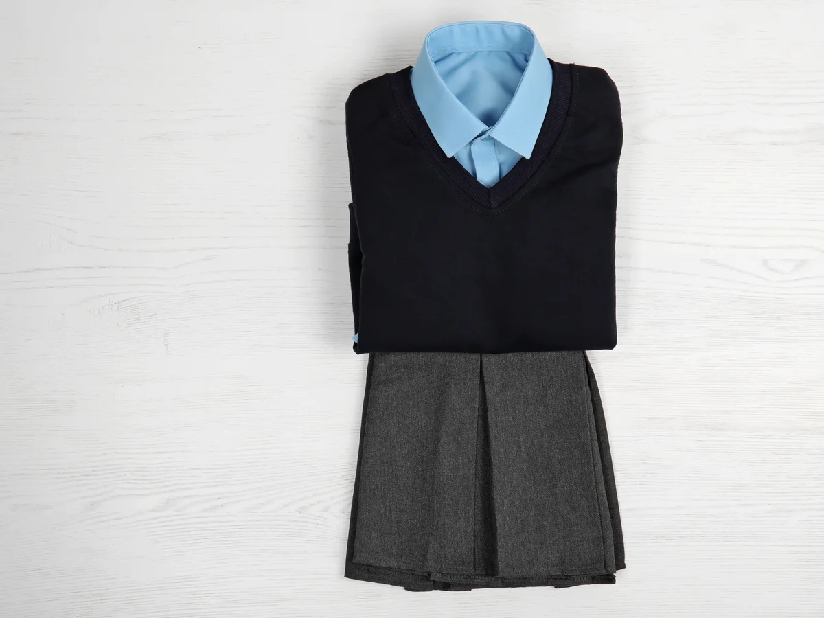School uniform with a blue shirt, dark vest and grey skirt