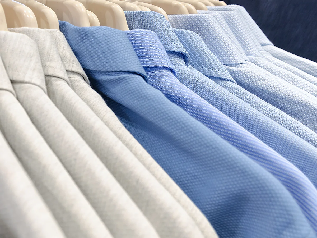 Polo shirts in white, grey and blue on a clothing rail