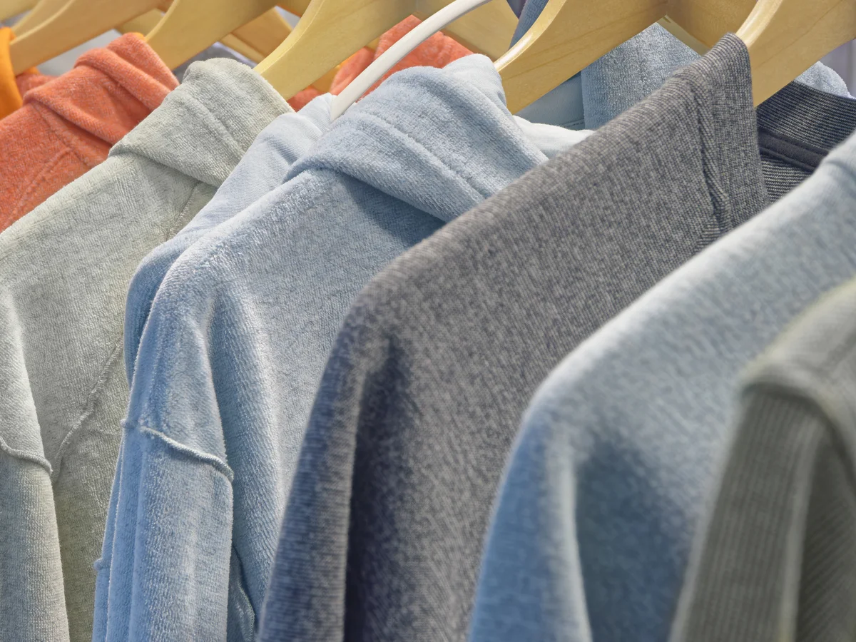 Sweatshirts in a range of colours on wooden hangers