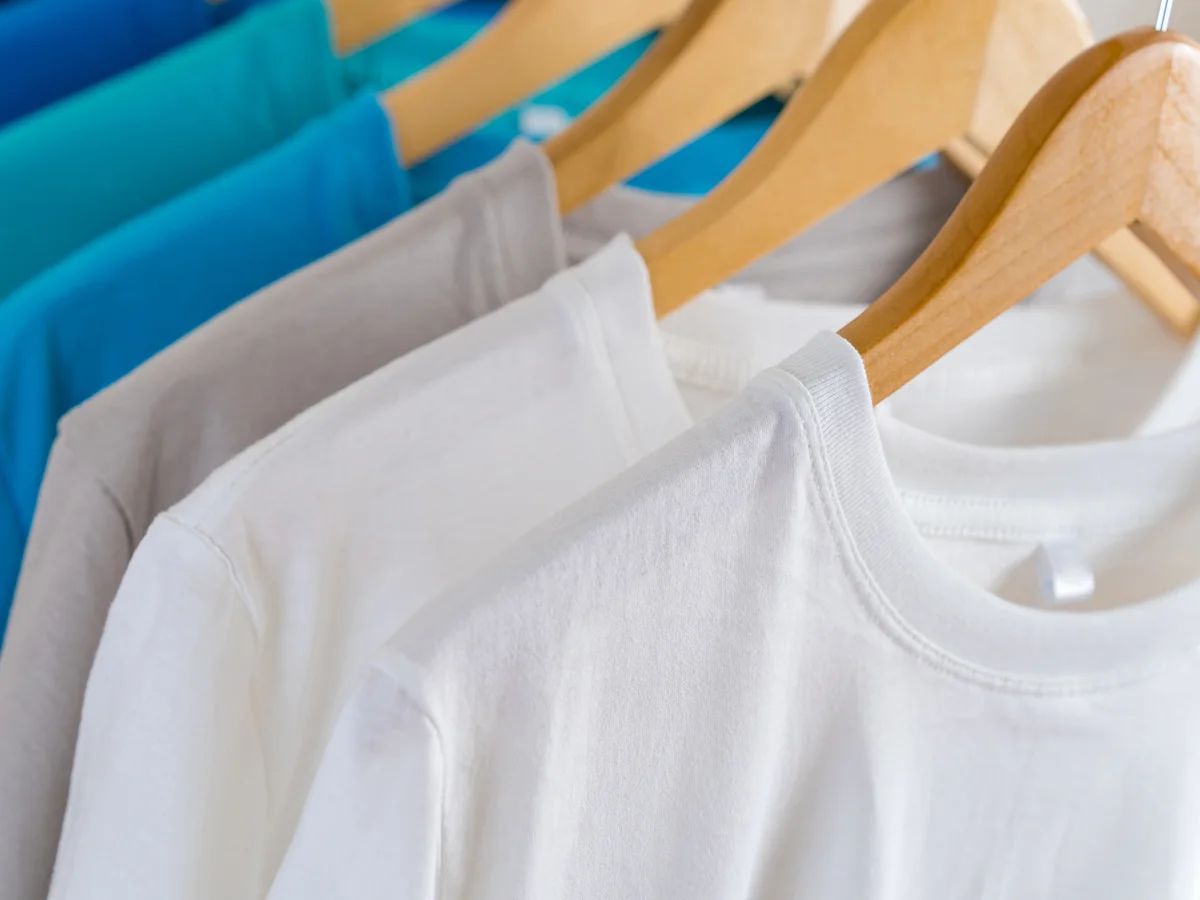 T-shirts in white, grey and blue on wooden hangers