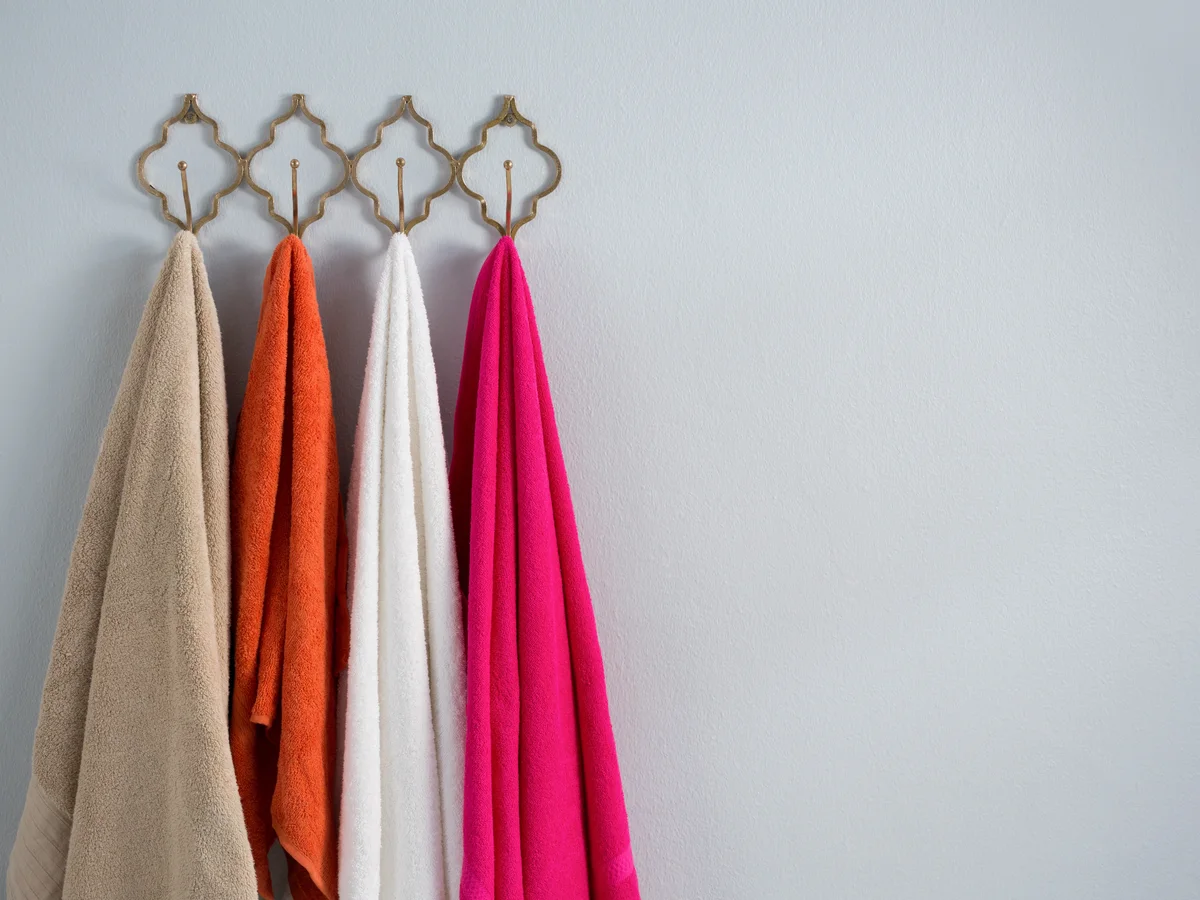 Towels in a range of colours hanging from wall hooks